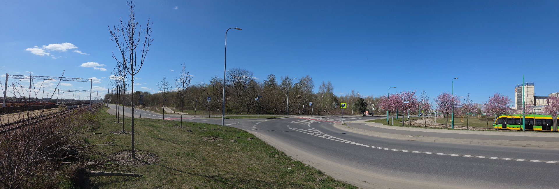 Folwarczna, działka inwestycyjna na sprzedaż, widok od strony skrzyżowania ul. Szwajcarskiej i Folwarcznej, widok nieruchomości (porośnięta gęsto roślinnością) i otoczenia - drogi, tory kolejowe, pętla tramwajowa, w oddali zabudowania